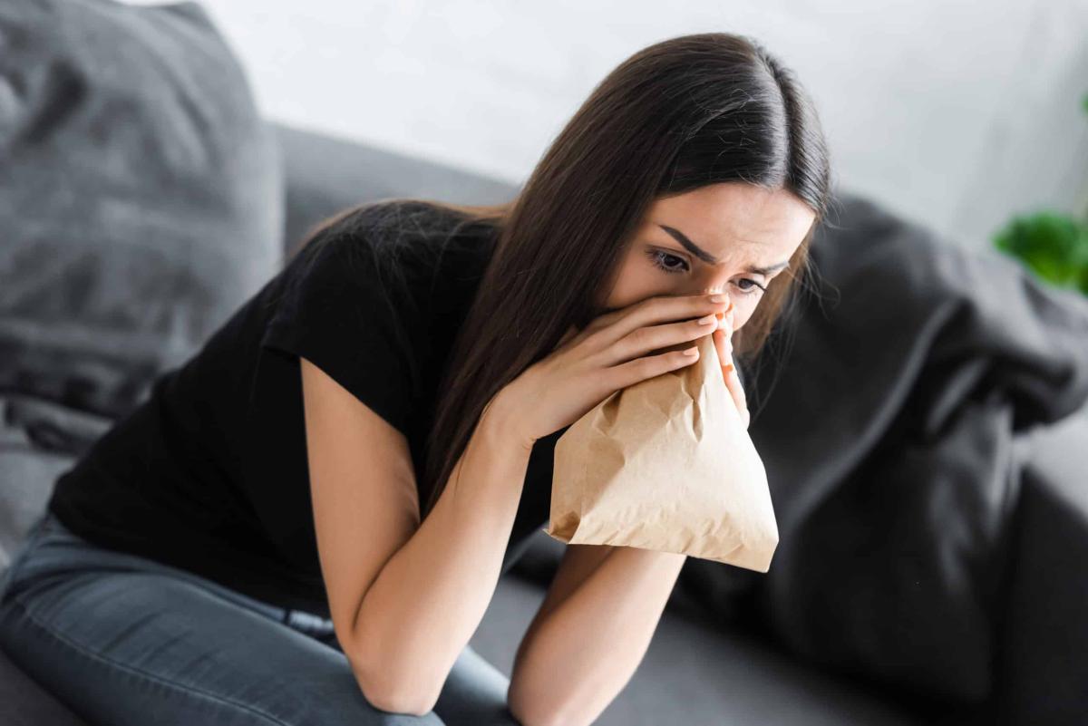 young woman breathing into paper bag while sufferi 2021 08 30 01 46 36 utc scaled 1