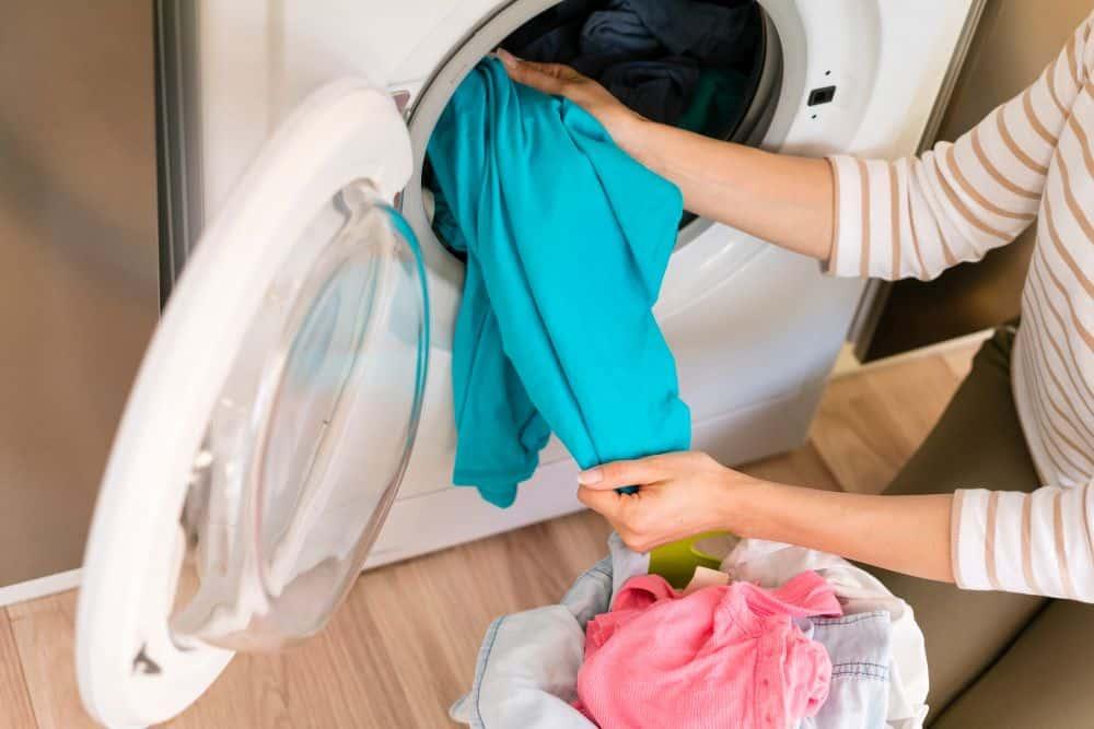 hands taking laundry out washing machine