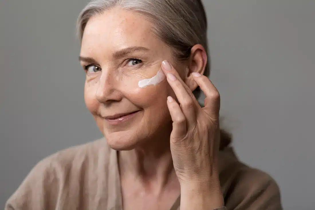 side view smiley woman applying face cream 1