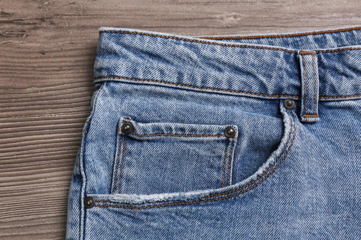 stylish light blue jeans on wooden background closeup of inset pocket 11zon