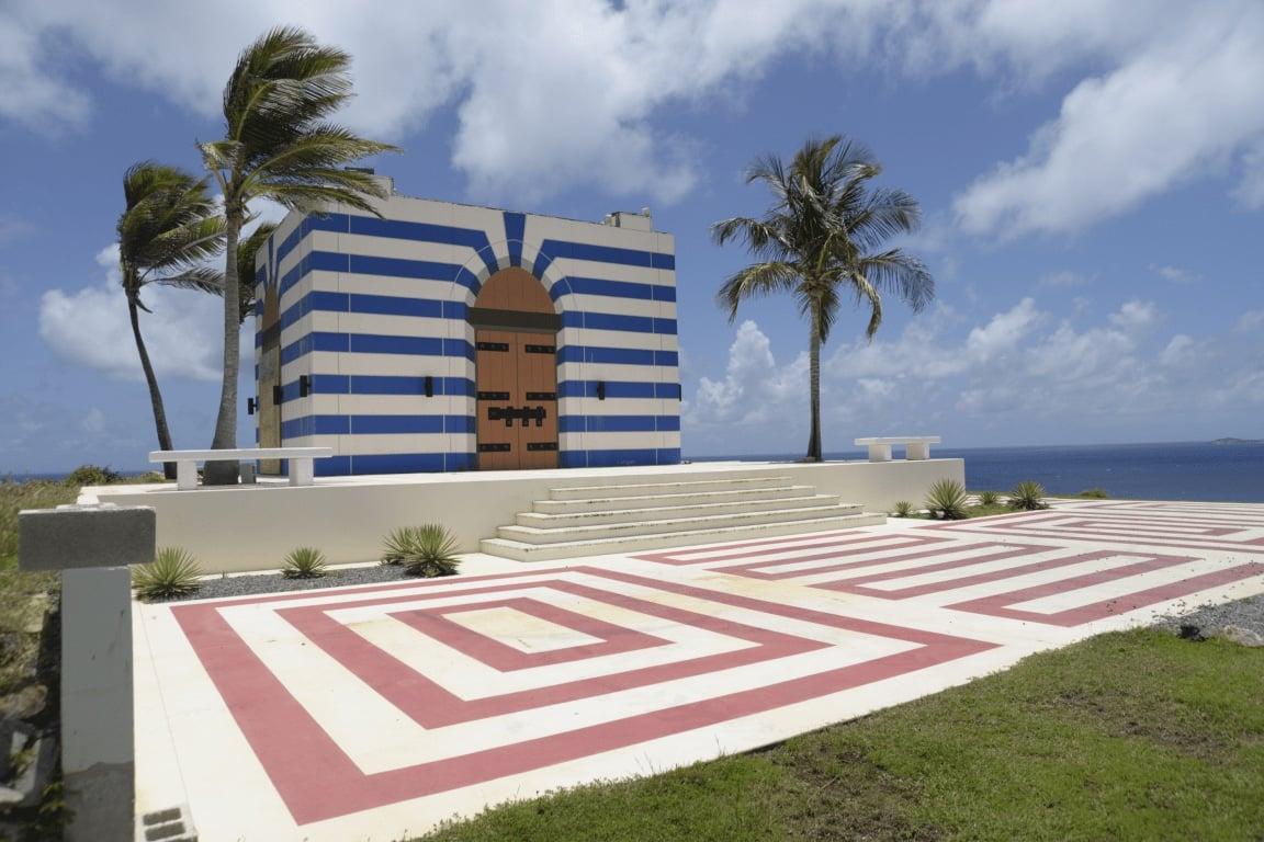 efta00002940 temple blue and white striped building with a red and white labyrinth in front set against a tropical backdrop of palm trees and the ocean under a bright sky